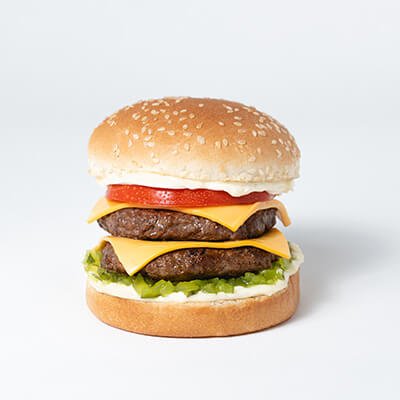 Hamburger in a white bun with two beef patties and two slices of cheese, tomato, mayonnaise, relish, ketchup, on a white background