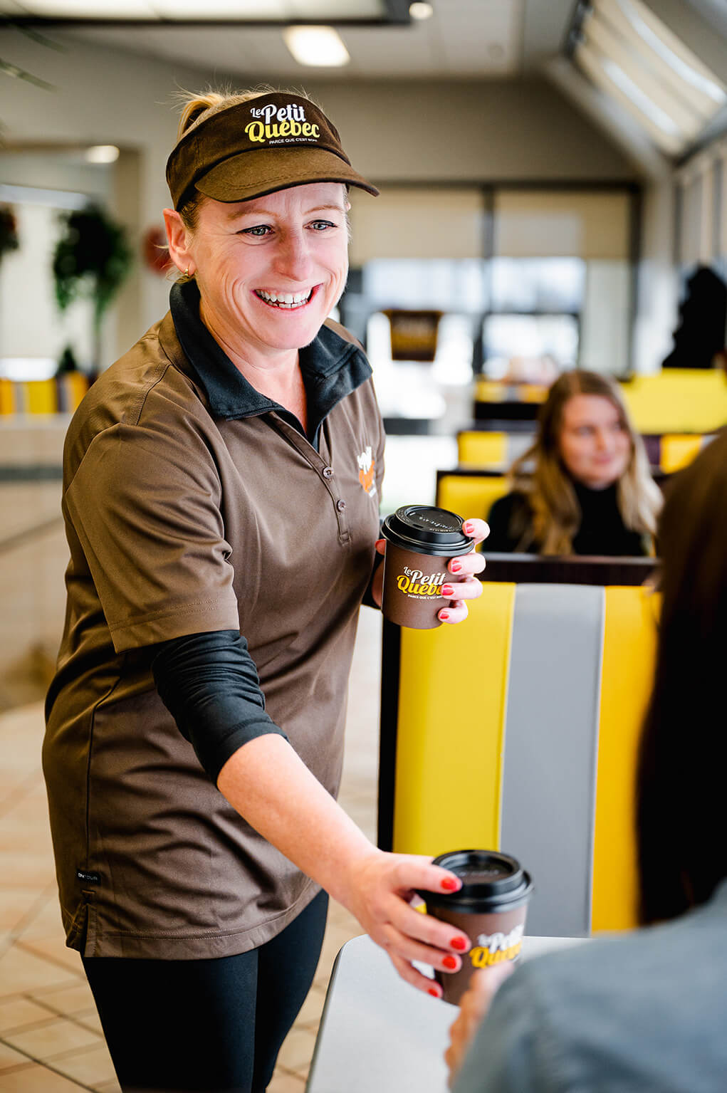Femme qui sert le café aux clients dans un restaurant fast-food Le Petit Québec