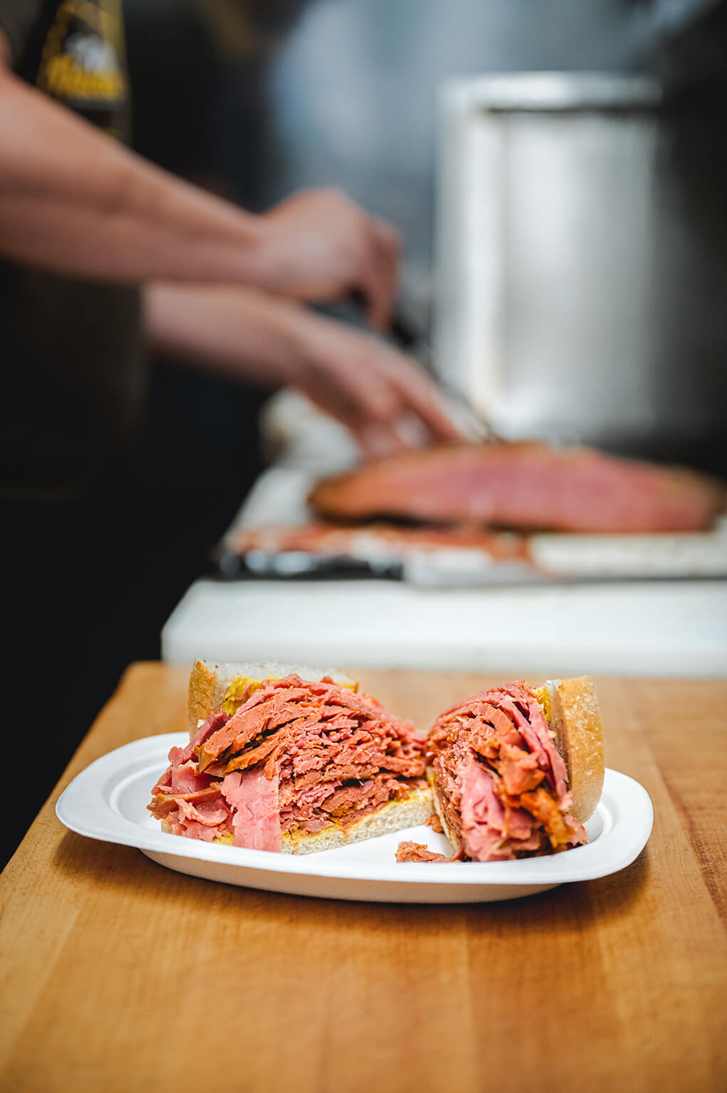 Smoked meat sandwich on a white plate in fast-food restaurant kitchen